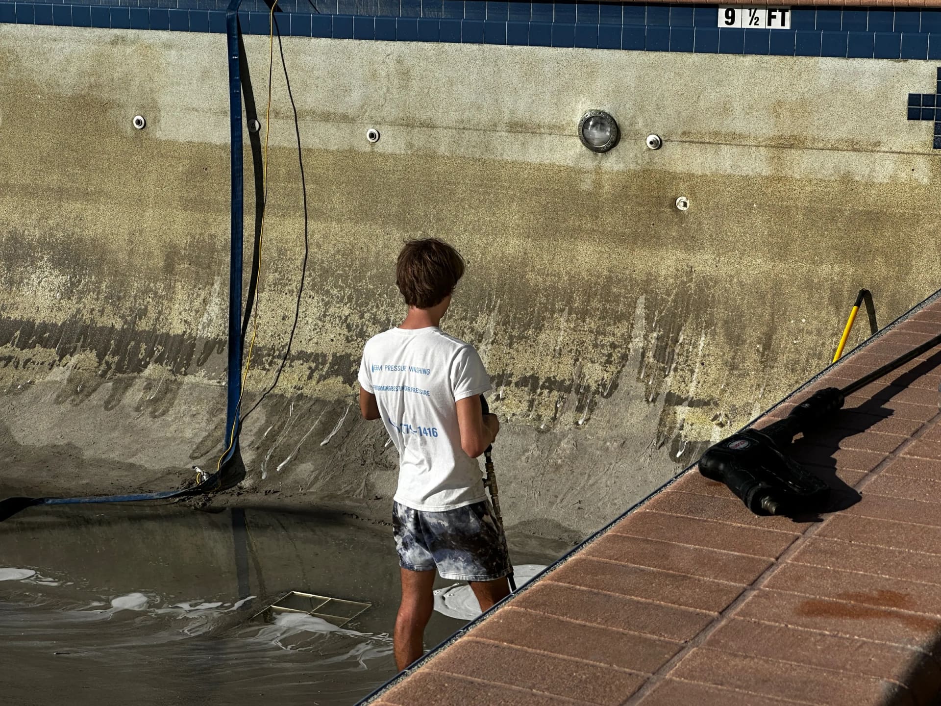Technician pressure washing inside pool shell at Regatta Beach Club