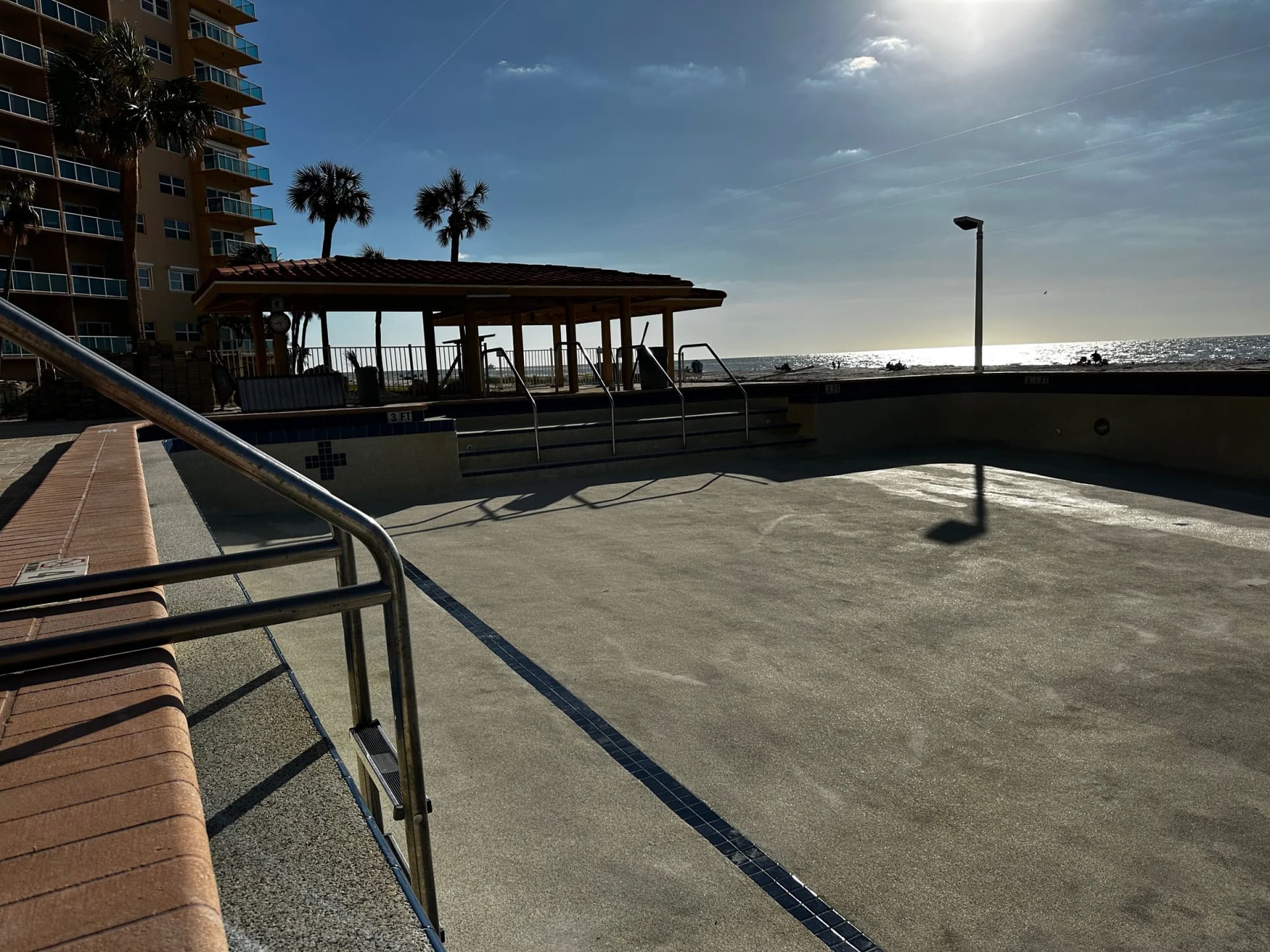 Drained commercial pool with visible storm residue during cleanup at Regatta Beach Club
