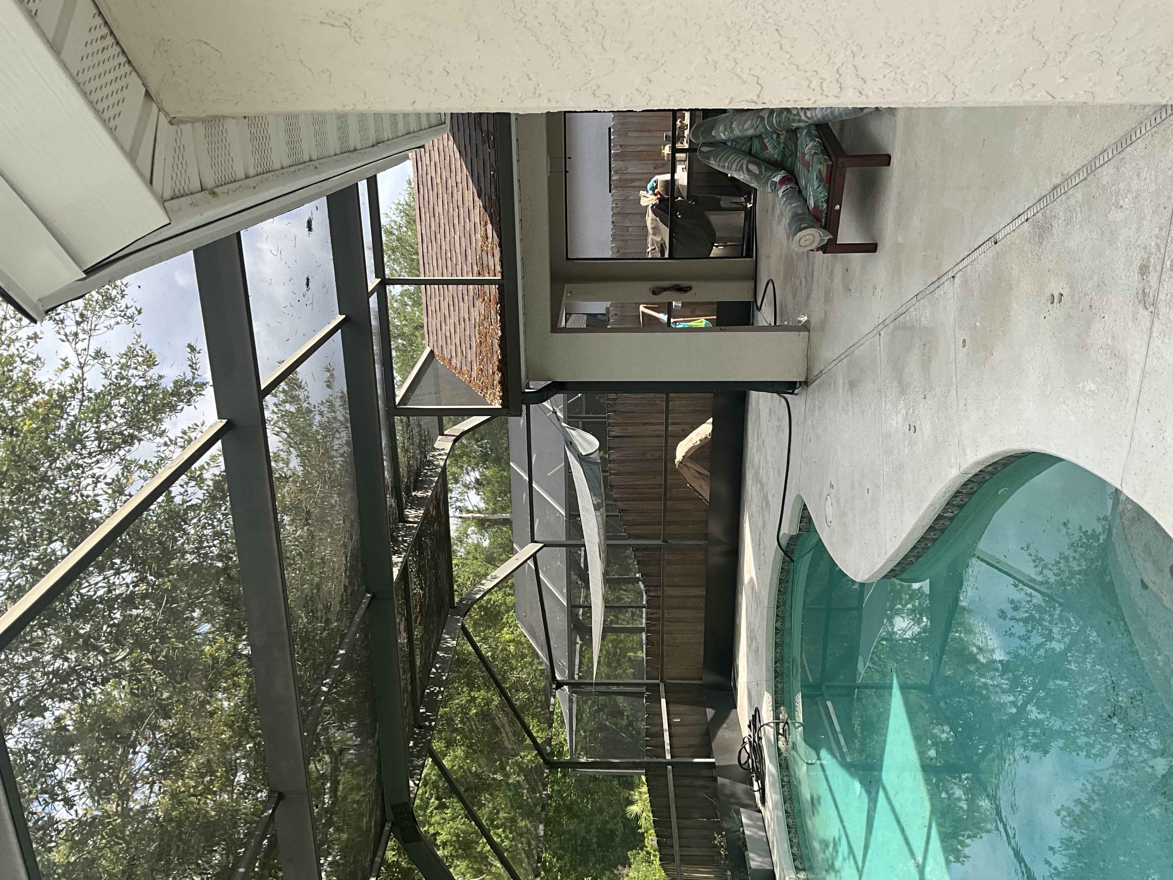 Pool deck cleaning in Tampa around a residential pool with a wider backyard deck view