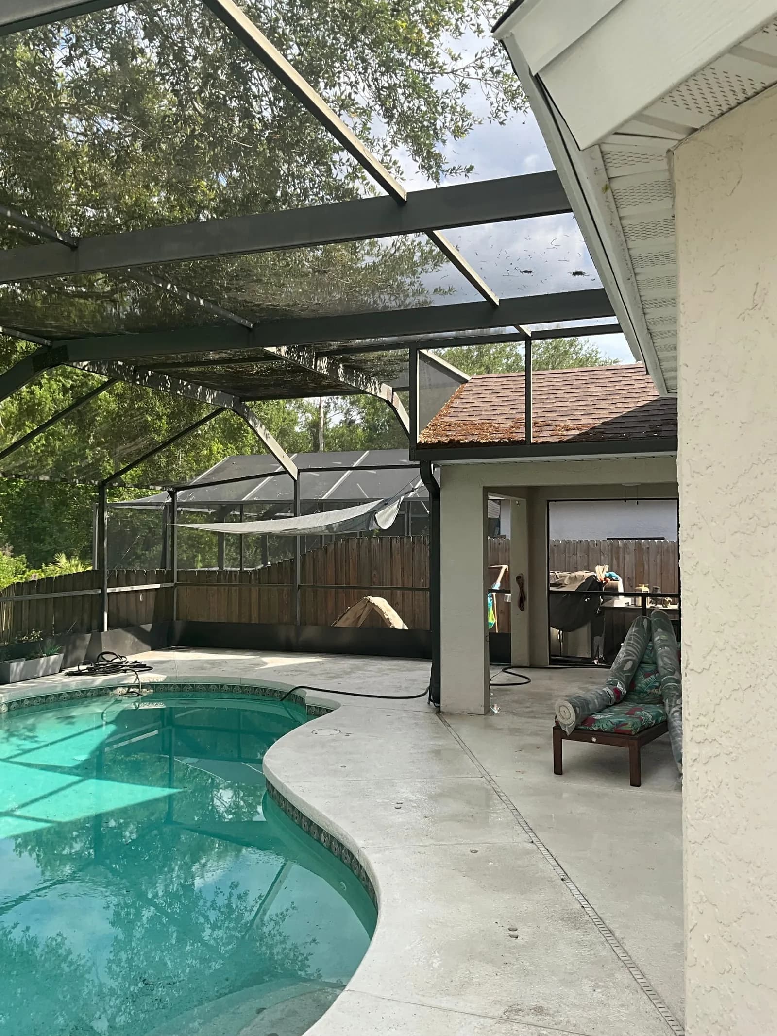Pool deck cleaning in Tampa with a wider backyard view and screened pool area