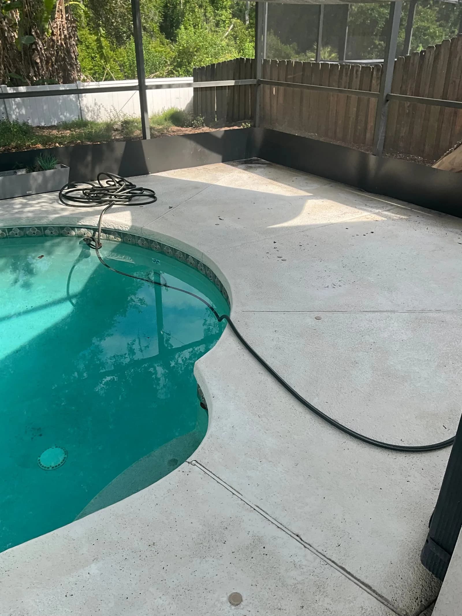 Pool deck surface in Tampa showing buildup along the deck edge near the water
